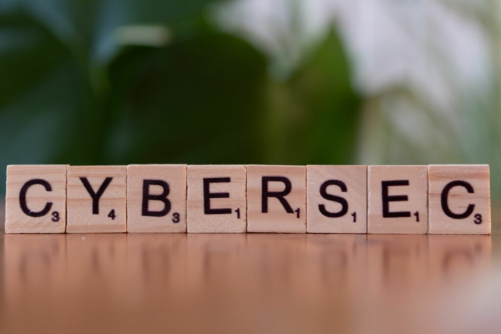 Wooden tiles spell 'CYBERSEC' against a soft-focused green background.